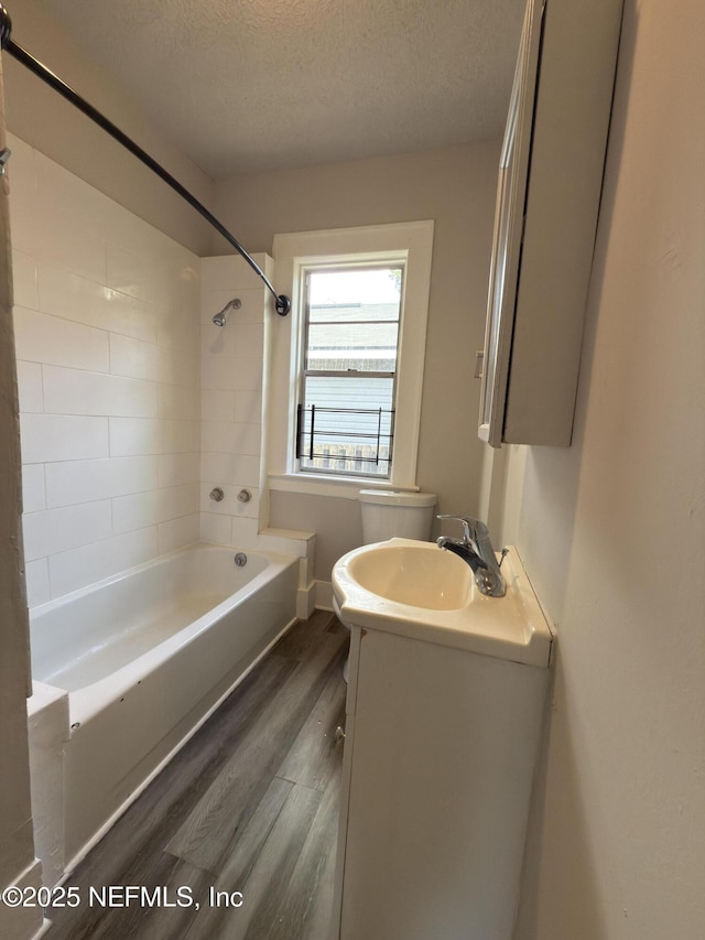 6624 Avalon St, Jacksonville, FL 32208 - bathroom featuring a textured ceiling, toilet, wood finished floors, vanity, and shower / washtub combination