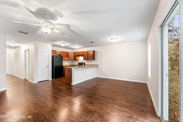 kitchen with black fridge, plenty of natural light, dark hardwood / wood-style floors, and kitchen peninsula