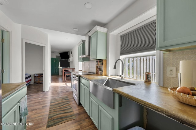 kitchen with decorative backsplash, green cabinetry, dark wood-type flooring, and stainless steel range with electric cooktop