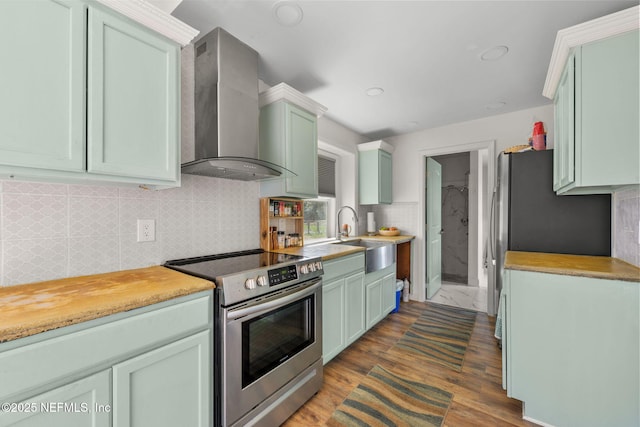 kitchen with stainless steel range with electric stovetop, green cabinets, sink, and wall chimney range hood