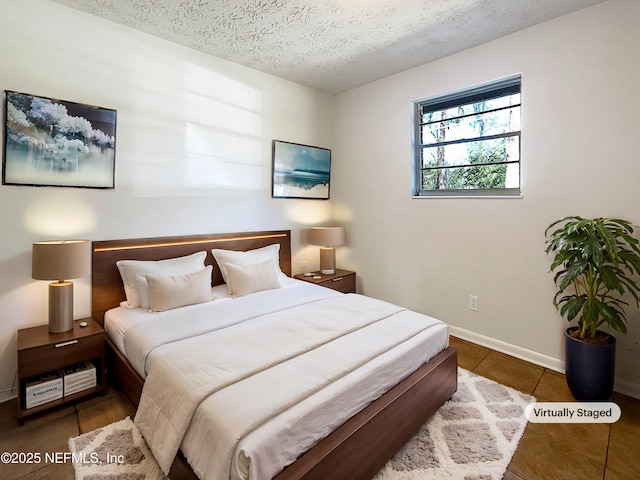 bedroom featuring baseboards, a textured ceiling, and dark tile patterned flooring