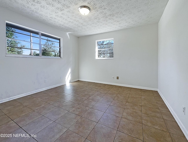 unfurnished room with baseboards, a textured ceiling, and tile patterned floors