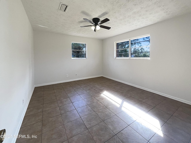 spare room with a ceiling fan, a healthy amount of sunlight, visible vents, and baseboards