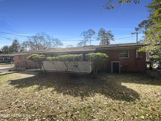 back of house featuring brick siding, a yard, fence, and central AC unit