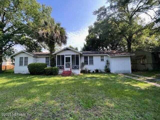 single story home featuring a garage, a front yard, a sunroom, and driveway