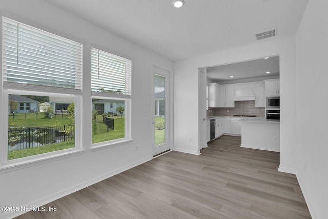 232 Fairlake Cir, Saint Augustine, FL 32092 - kitchen with appliances with stainless steel finishes, light countertops, white cabinetry, light wood-style flooring, and tasteful backsplash
