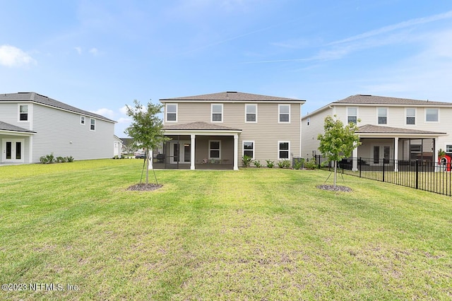 rear view of house featuring a sunroom, fence, and a yard