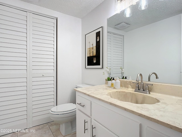 bathroom with tile patterned flooring, vanity, a textured ceiling, and toilet