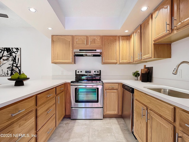 kitchen with light tile patterned flooring, sink, appliances with stainless steel finishes, a tray ceiling, and exhaust hood