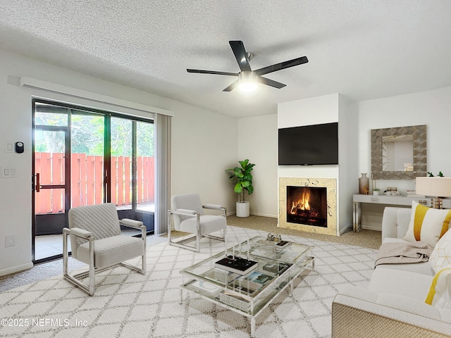 carpeted living room featuring a premium fireplace, ceiling fan, and a textured ceiling