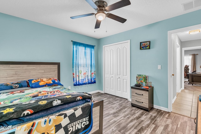 bedroom featuring ceiling fan, wood-type flooring, a closet, and a textured ceiling