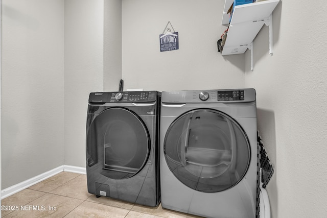 clothes washing area with washer and dryer and light tile patterned floors