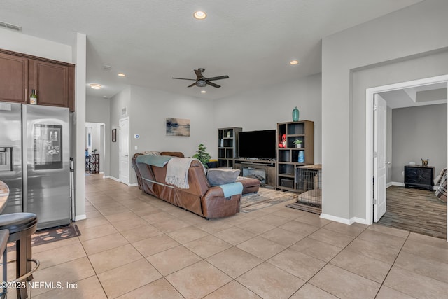 living room with ceiling fan, a textured ceiling, and light tile patterned floors