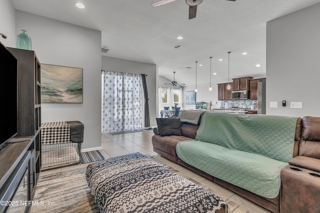 living room with ceiling fan, a textured ceiling, and light tile patterned floors