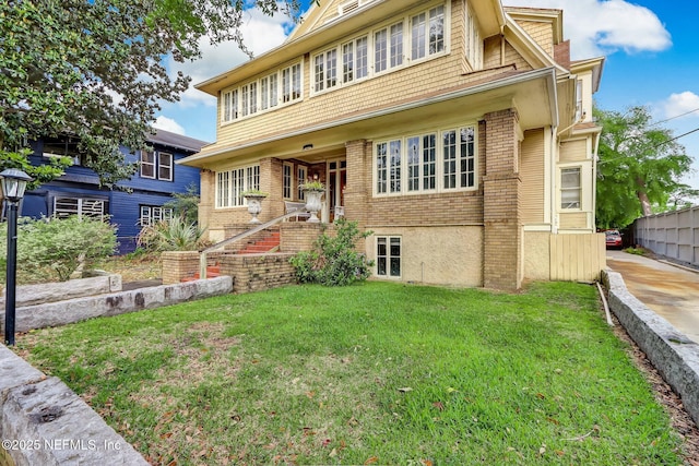 view of front of house featuring a front lawn, fence, and brick siding