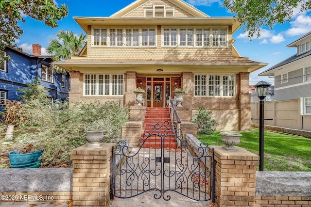 shingle-style home featuring brick siding, fence, and a gate