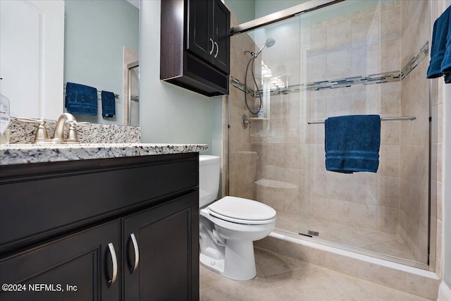 bathroom featuring vanity, toilet, a shower with shower door, and tile patterned flooring