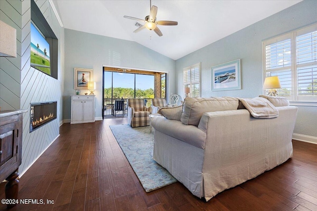 living room with a wealth of natural light, dark wood-type flooring, a large fireplace, and ceiling fan