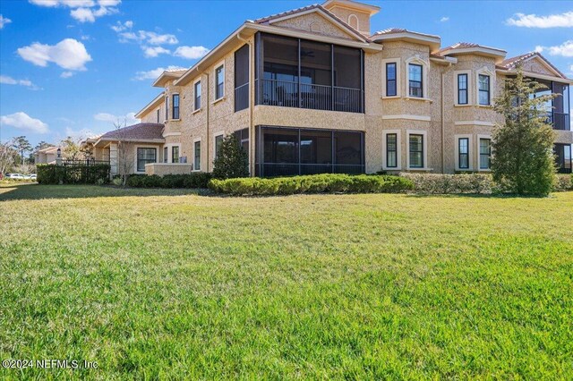 rear view of property with a yard and a sunroom