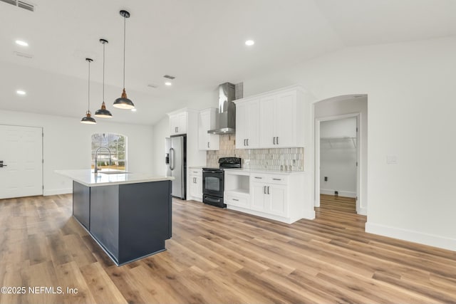 kitchen featuring stainless steel fridge, wall chimney exhaust hood, black range with electric stovetop, and white cabinets