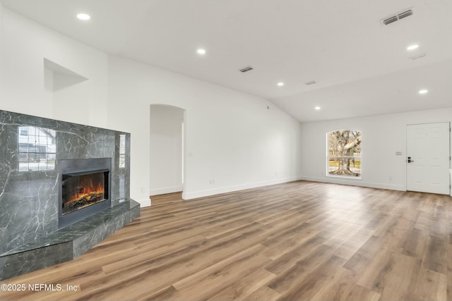 unfurnished living room featuring a fireplace, wood-type flooring, and vaulted ceiling