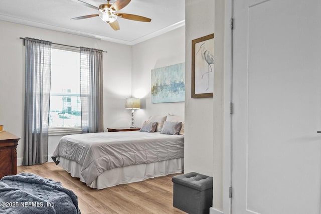 bedroom with ceiling fan, ornamental molding, and light wood-type flooring