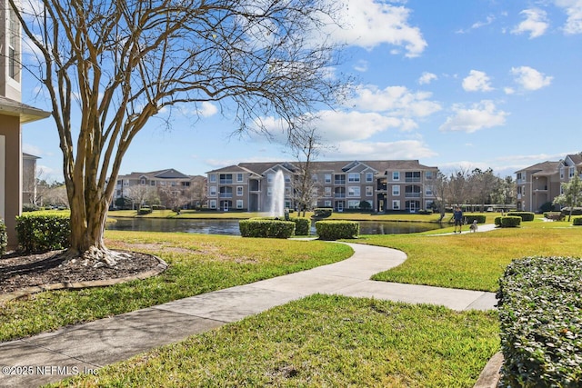 view of property's community featuring a lawn and a water view