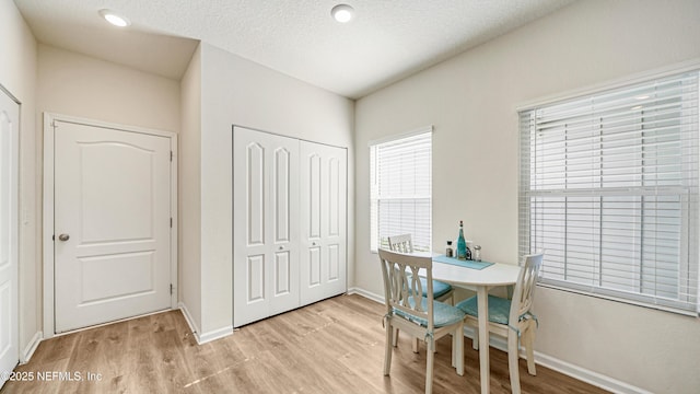 office area with light wood-style flooring, baseboards, and a textured ceiling