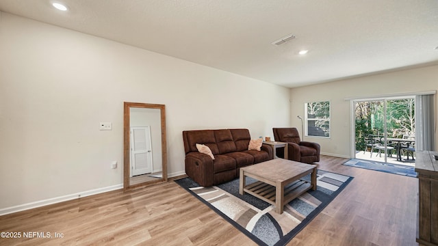 living room with light wood-type flooring, visible vents, baseboards, and recessed lighting