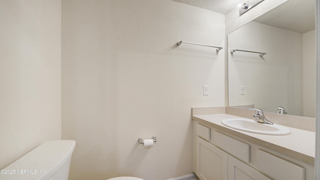 half bath featuring vanity, toilet, and a textured ceiling