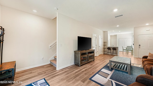 living room featuring baseboards, visible vents, stairs, light wood-style floors, and recessed lighting