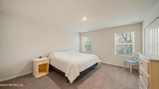 bedroom with baseboards, a textured ceiling, and light colored carpet