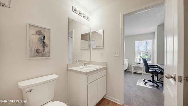 bathroom featuring toilet, baseboards, a textured ceiling, and vanity