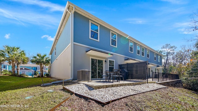 back of house with stucco siding, a yard, fence, and central air condition unit