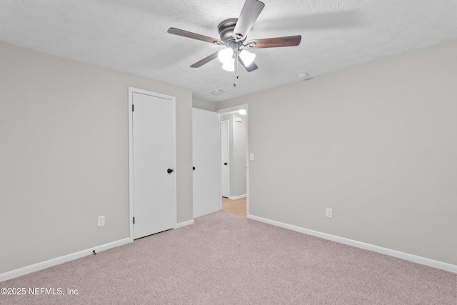 unfurnished bedroom featuring ceiling fan, light colored carpet, and a textured ceiling