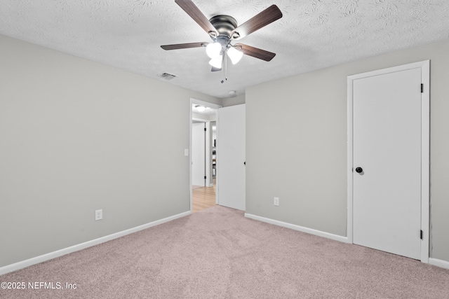 unfurnished bedroom with ceiling fan, light colored carpet, and a textured ceiling