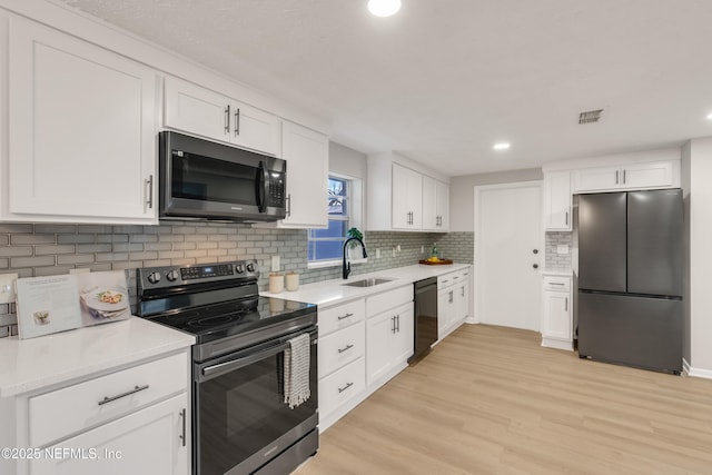 kitchen featuring tasteful backsplash, sink, white cabinets, stainless steel appliances, and light wood-type flooring