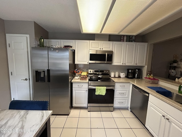 kitchen featuring stainless steel appliances, white cabinetry, sink, and light tile patterned floors