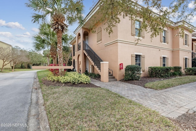 view of property exterior featuring stairs, a lawn, and stucco siding