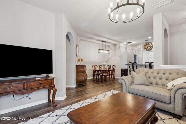 living room featuring arched walkways, wood finished floors, visible vents, and a chandelier