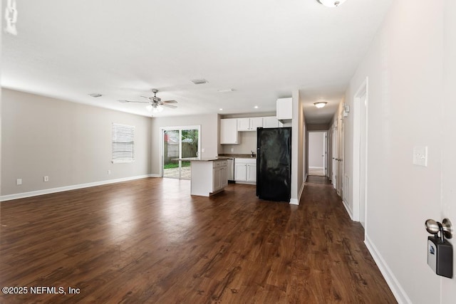 unfurnished living room with dark wood-type flooring and ceiling fan