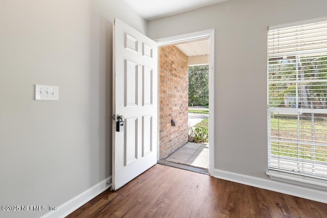 foyer entrance featuring brick wall, plenty of natural light, and hardwood / wood-style floors