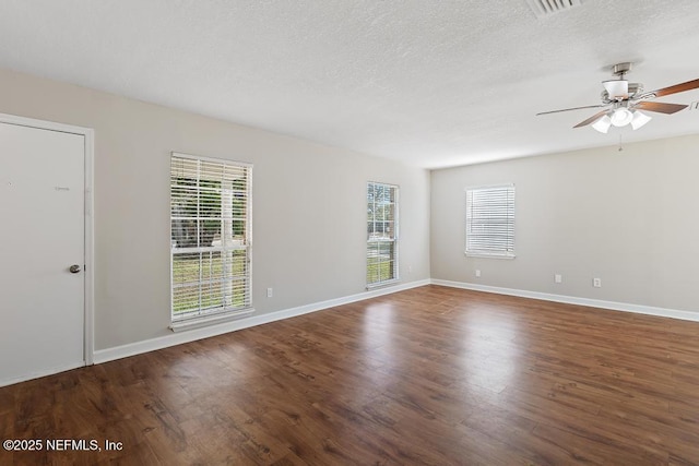 empty room featuring plenty of natural light, a textured ceiling, and dark hardwood / wood-style flooring