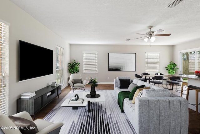 living room featuring dark hardwood / wood-style flooring, a textured ceiling, and ceiling fan