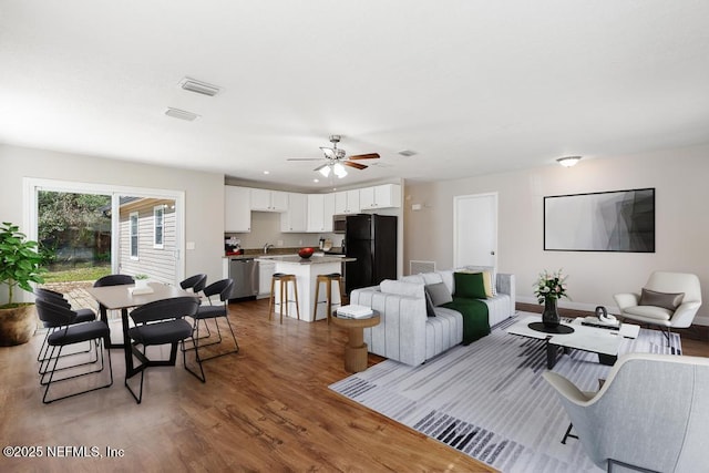 living room with hardwood / wood-style flooring, sink, and ceiling fan