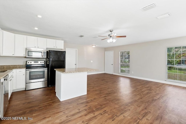 kitchen with white cabinetry, light stone countertops, a center island, and appliances with stainless steel finishes