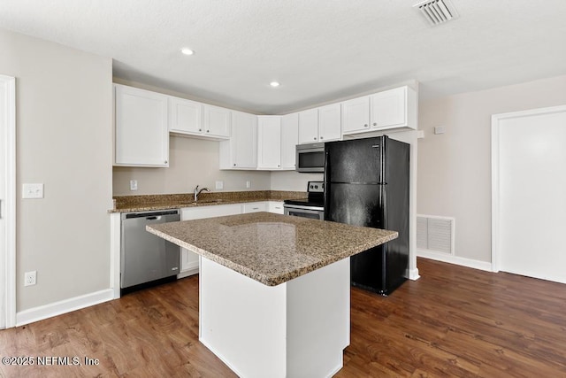 kitchen with sink, a center island, appliances with stainless steel finishes, light stone countertops, and white cabinets