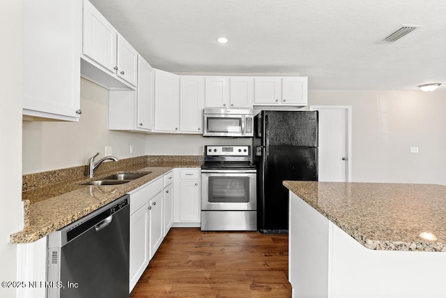 kitchen featuring sink, light stone countertops, white cabinets, and appliances with stainless steel finishes