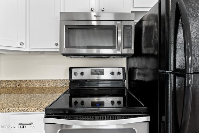 kitchen with appliances with stainless steel finishes, white cabinets, and light stone counters