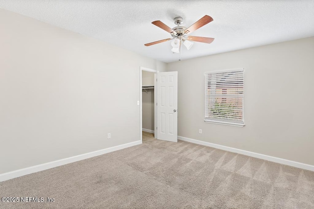 unfurnished bedroom featuring a spacious closet, ceiling fan, light carpet, a textured ceiling, and a closet